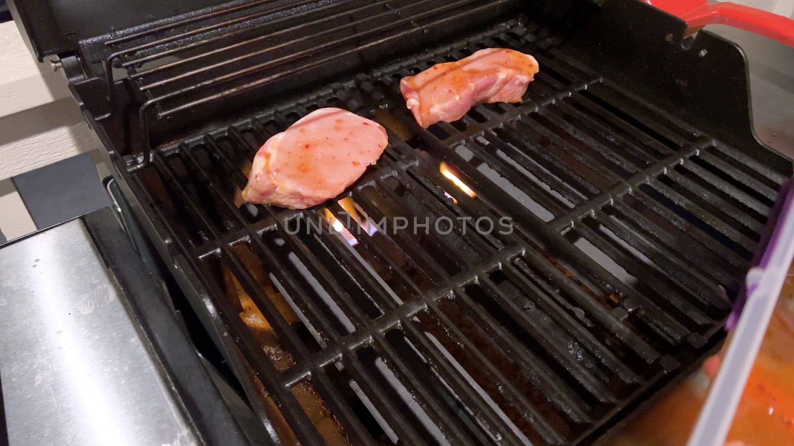 Perfectly Seasoned Pork Chops Sizzling on an Outdoor Gas Grill by arinahabich