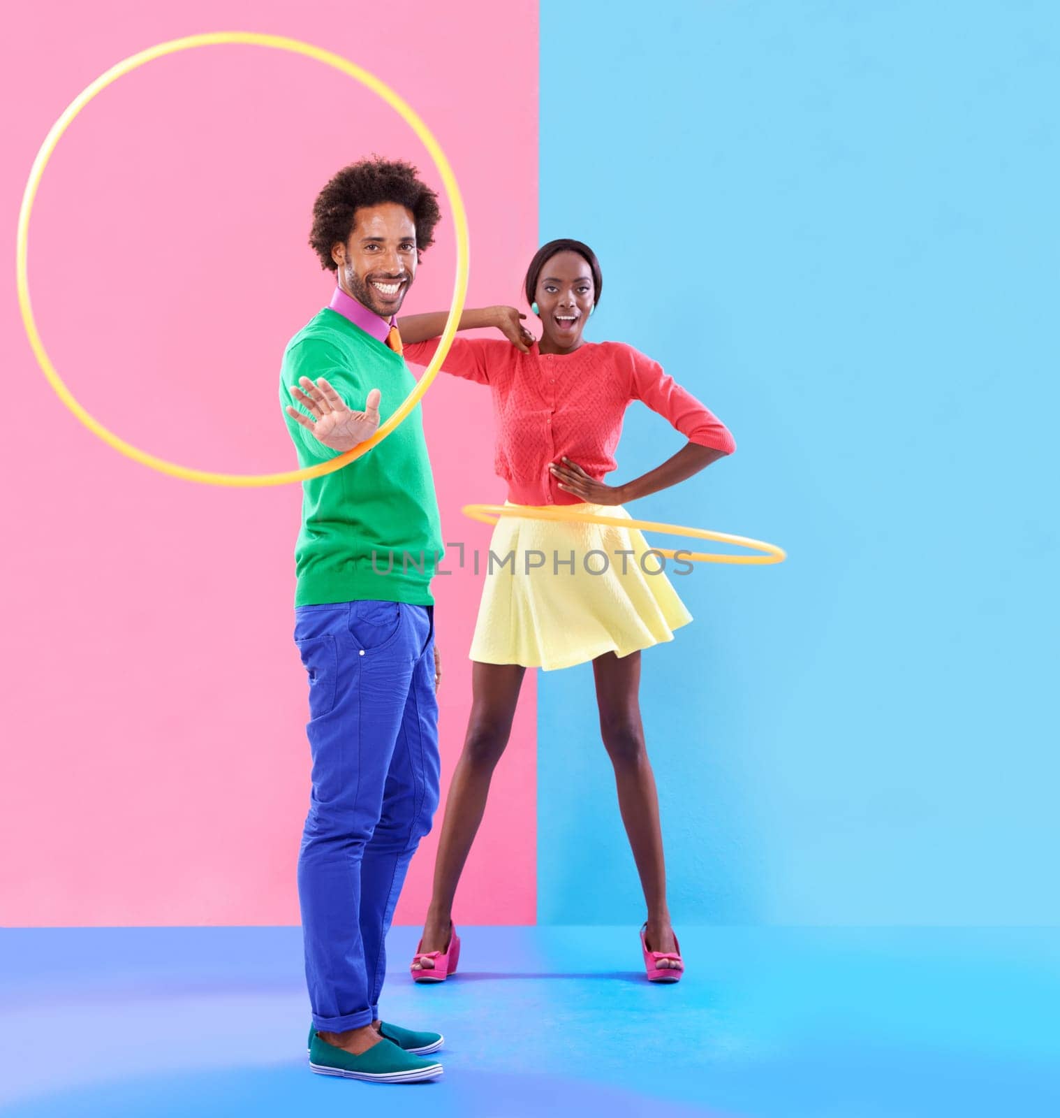 Couple, fashion and trendy in studio with colour clothes, smile and playful expression on black people together. Artistic, aesthetic in retro style for unique designer, summer fun and hula hoop by YuriArcurs
