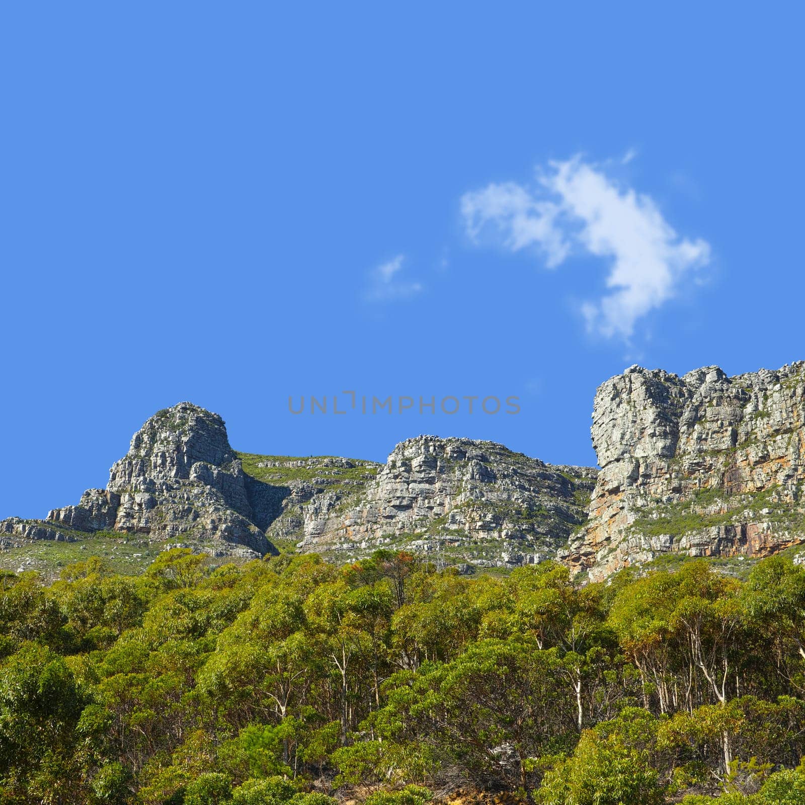 Mountains, sunshine and blue sky with nature, clouds and stone with landscape and environment. Empty, rock and grass with flowers or countryside with summer and travel with holiday, journey or plants.