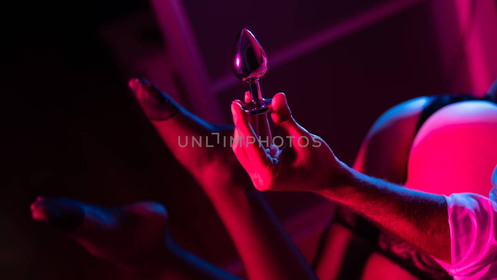 Man holding an anal plug. Close-up of female buttocks in underwear. Sexual preferences of the couple
