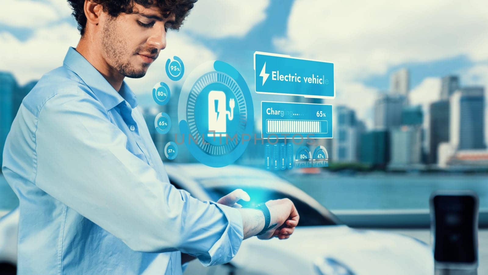 Businessman checking EV car battery status in hologram from smartwactch while recharging electricity from charging station on cityscape background. Alternative sustainable energy utilization. Peruse