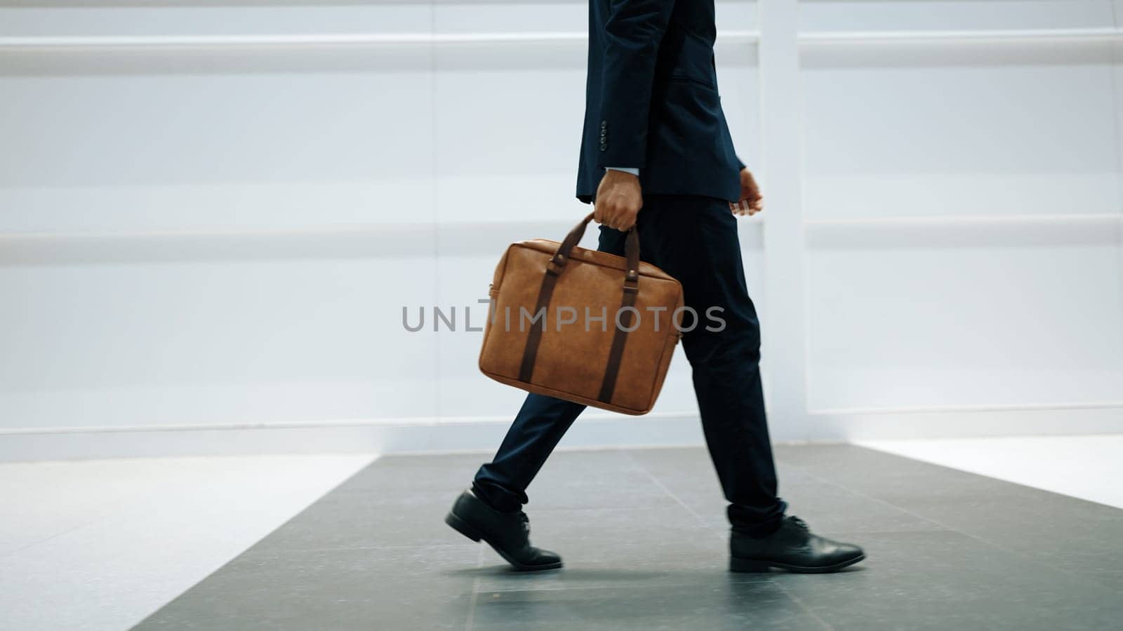 Closeup of professional business man leg walking while holding bag. Exultant. by biancoblue