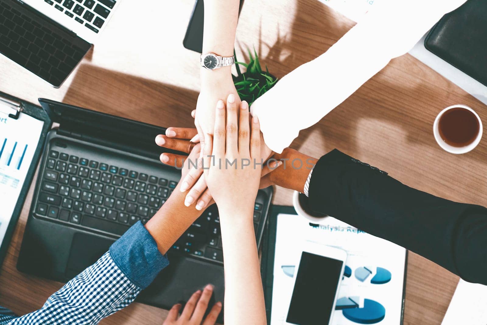 Businessmen and businesswomen joining hands in group meeting at multicultural office room showing teamwork, support and unity in business. Diversity workplace and corporate people working concept. uds