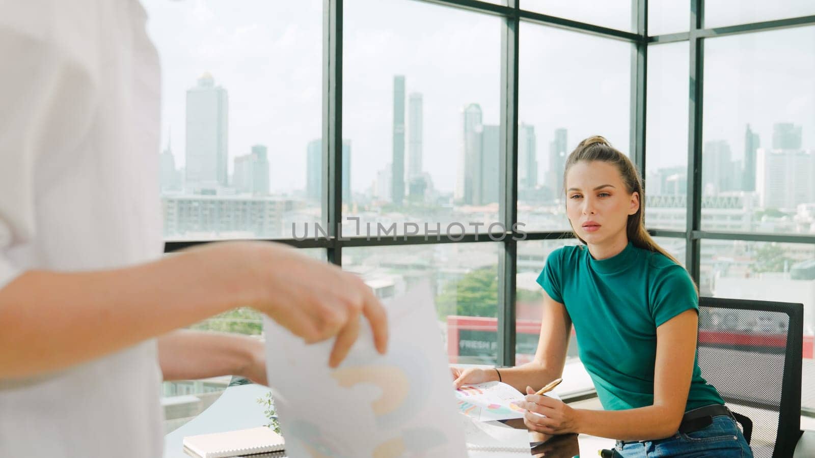 Professional female investor listening businessman present start up project statistic. Back view of businessman shows graph while manager using laptop analysis data at cityscape view. Tracery