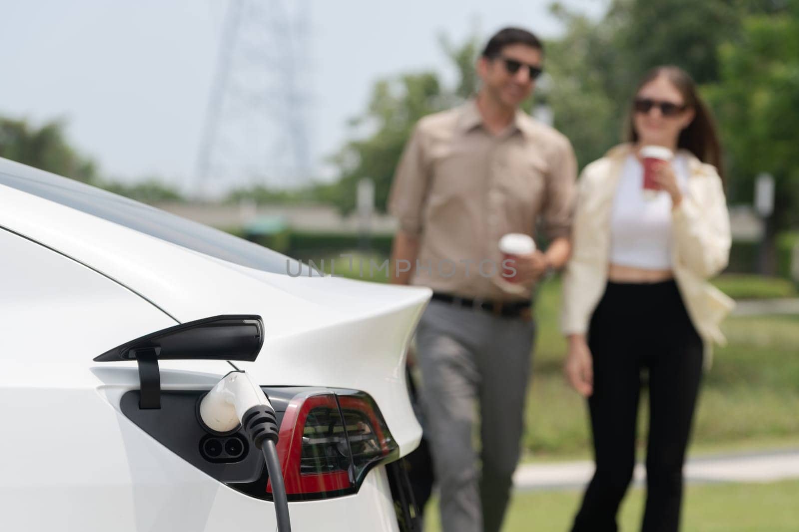 Young couple put EV charger to recharge electric car battery. Expedient by biancoblue