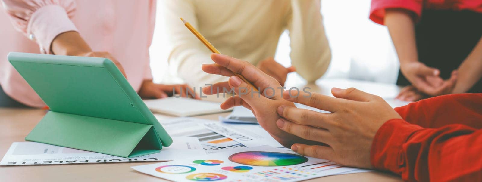 Creative design team discusses about interior design at meeting. Business people brainstorming about choosing color for project at modern office on table with color palette scatter around. Variegated.