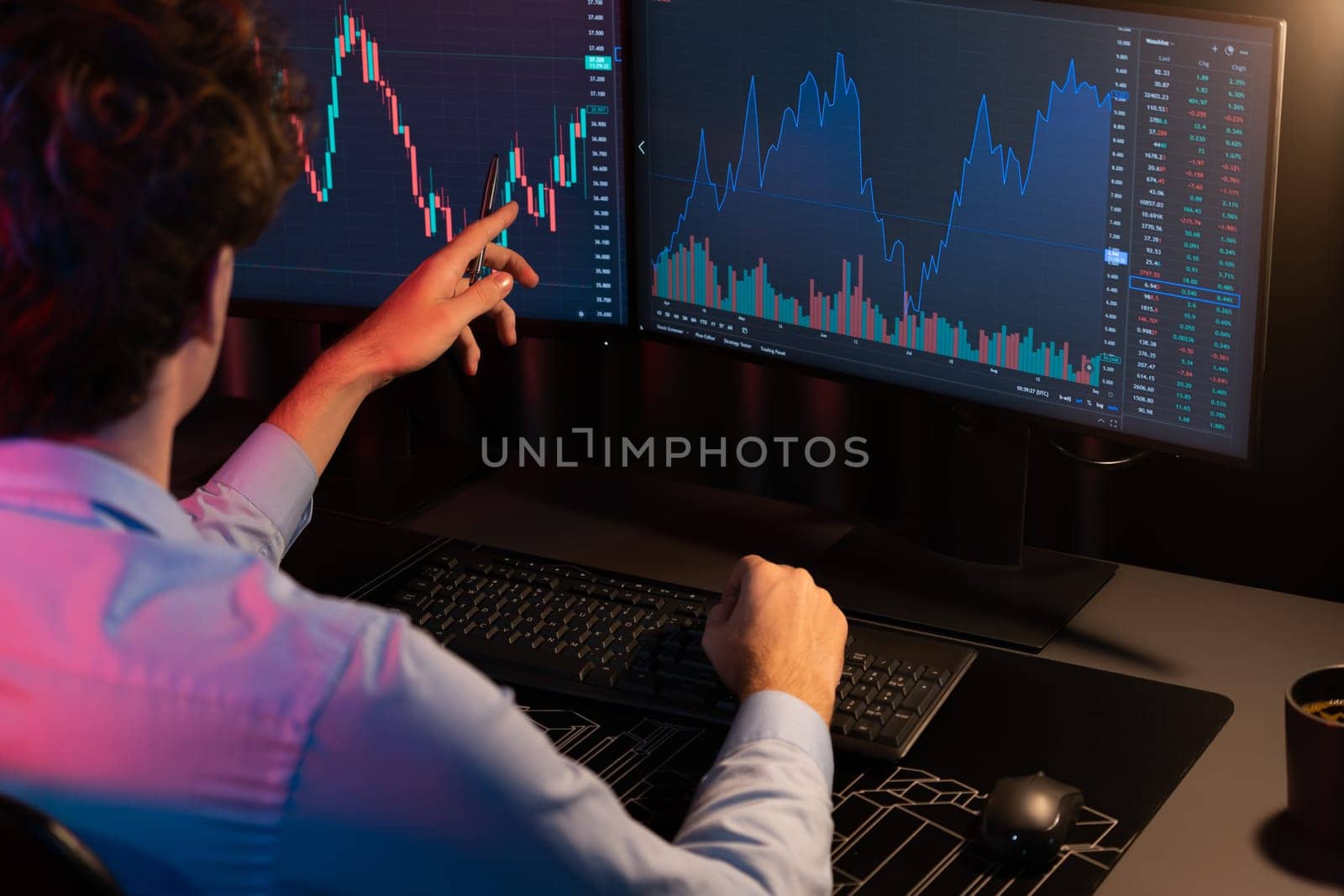 Working young business trader pointing on market stock graph data planning in real time monitor with back side view at neon modern office. Concept of analyzing dynamic financial exchange rate. Gusher.