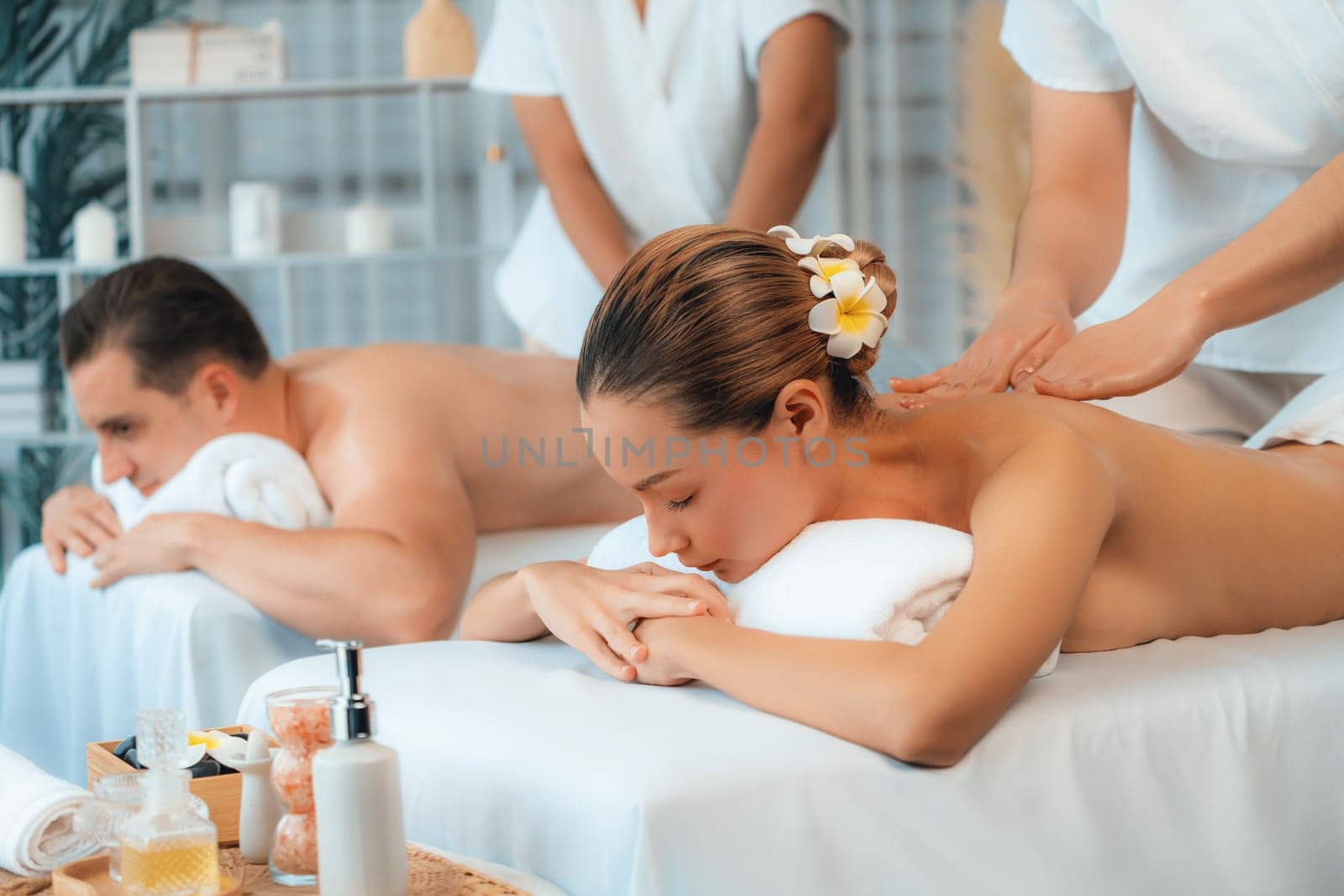 Caucasian couple customer enjoying relaxing anti-stress spa massage and pampering with beauty skin recreation leisure in day light ambient salon spa at luxury resort or hotel. Quiescent