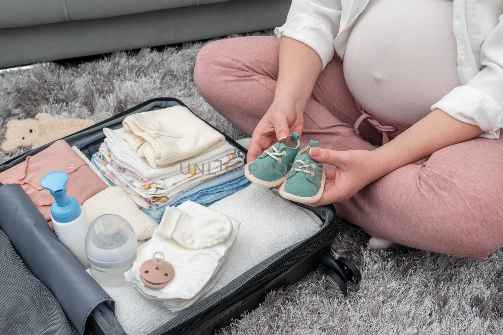Expecting mother holding baby shoes. Maternity prenatal care concept
