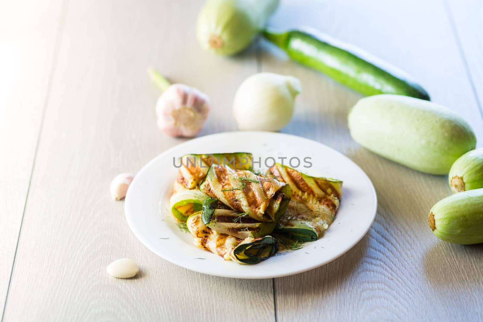 Grilled zucchini pieces with garlic sauce in a white plate. by Rawlik