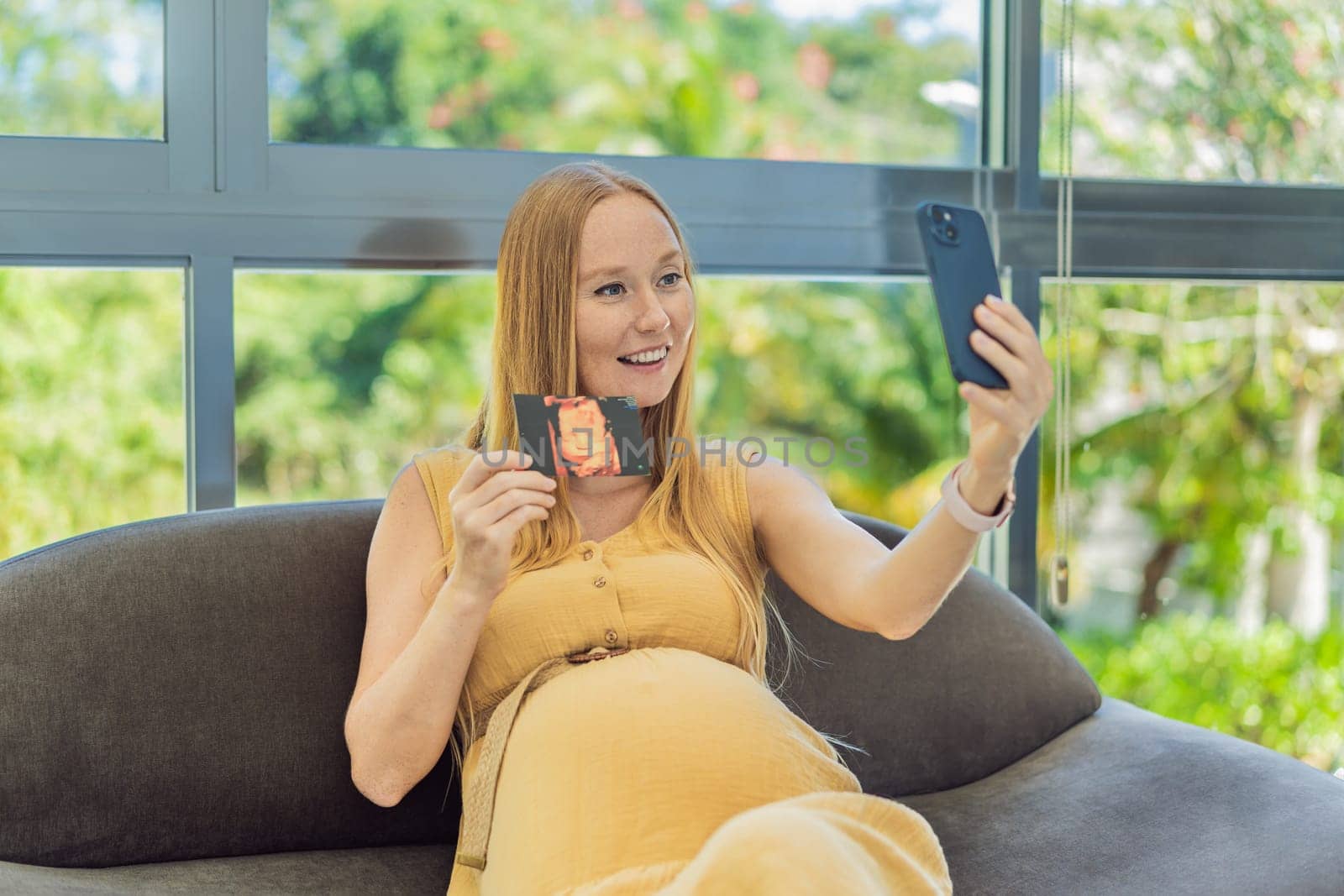 Excited woman shares the joy of motherhood, displaying an ultrasound photo of her child via a heartwarming video cal.