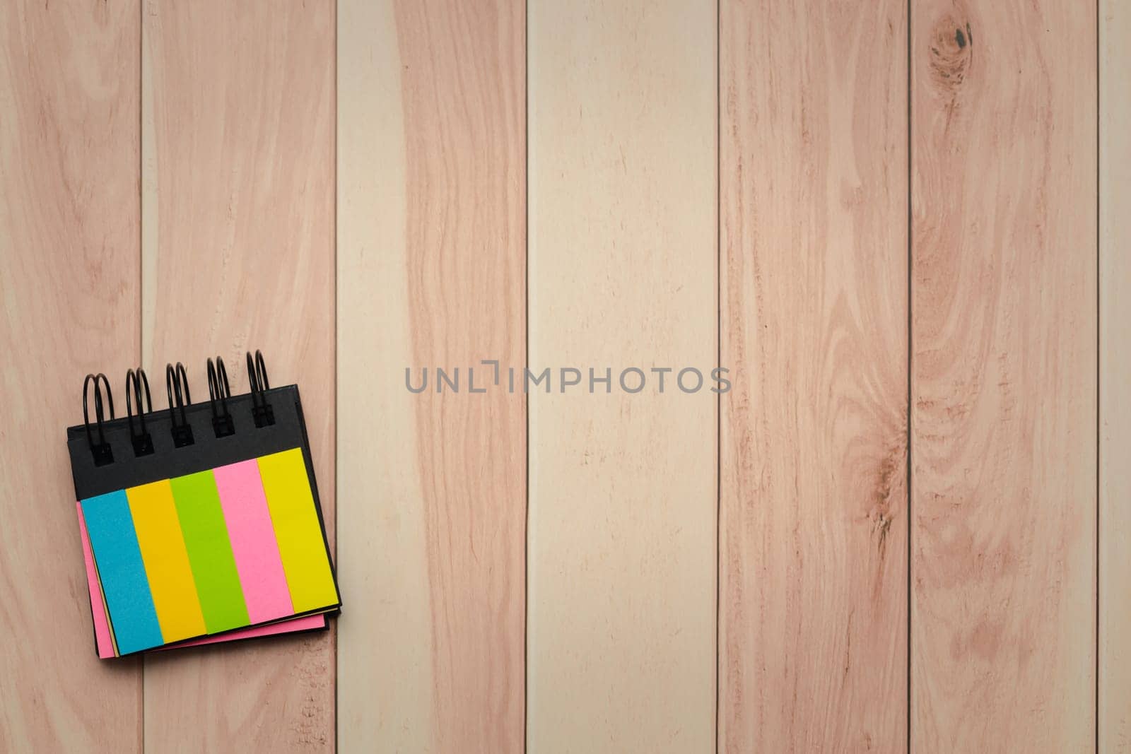 Top view of colorful notepad with copy space on wooden background. by iamnoonmai