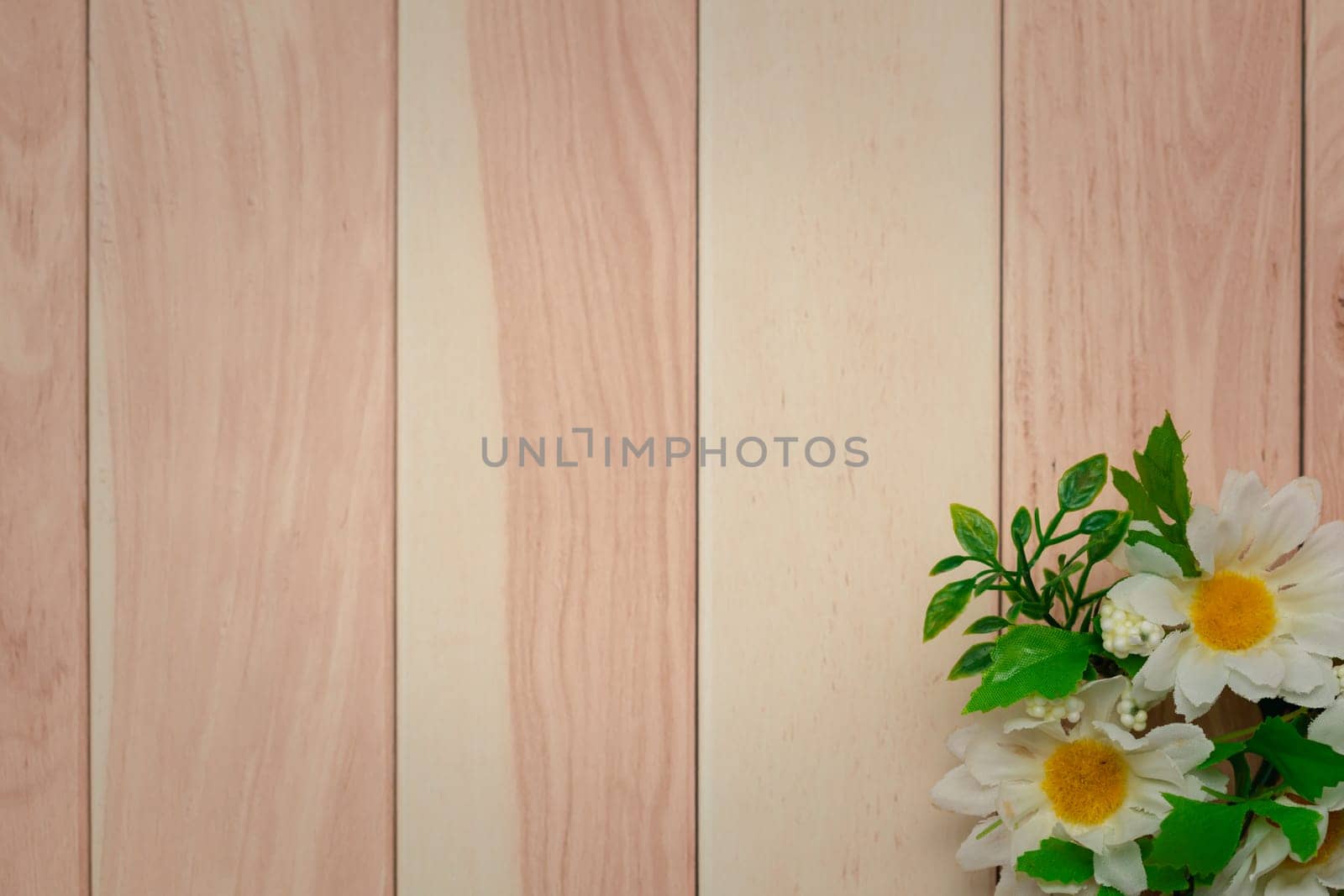 A bouquet of white daisies lying on a rustic; a brown stain and visible natural grain wooden table with copy space for text.