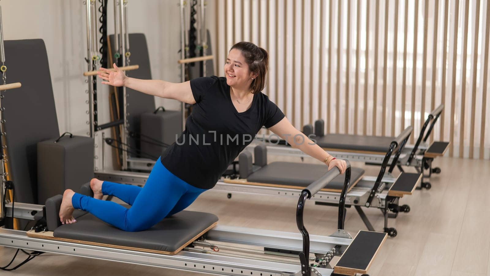 Overweight caucasian woman doing pilates exercises on a reformer