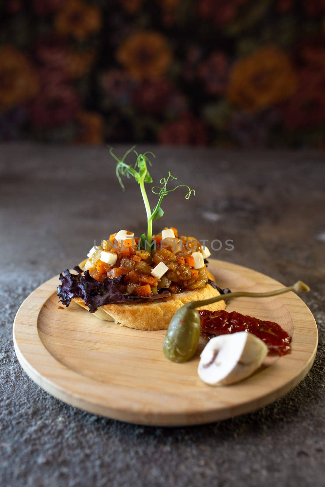 Rustic wooden plate with open faced sandwich with beef tenderloin and roasted mushrooms, garnished with fresh sprouts.