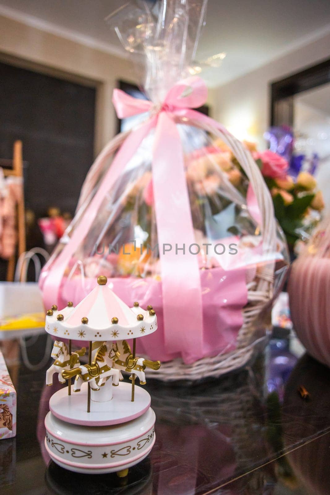 Elegant Baby Shower Gift Basket with Pink Bow and Carousel on Table by Pukhovskiy