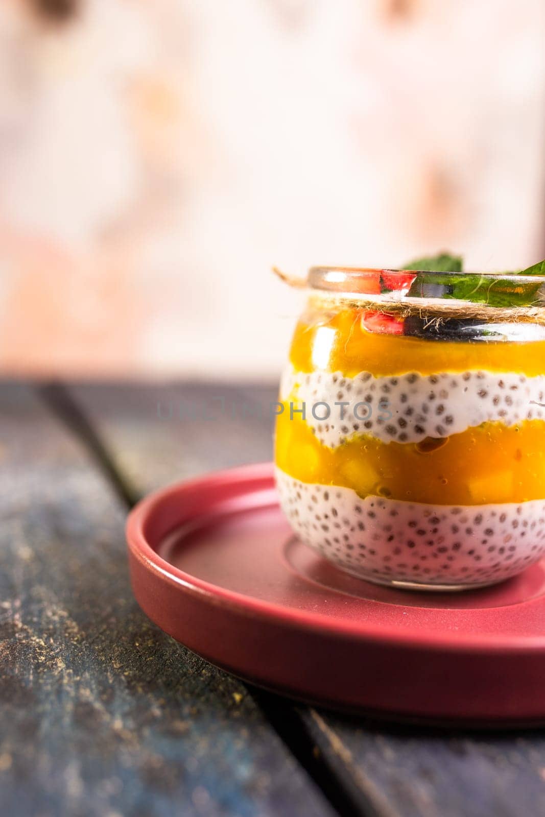 Chia Seed Pudding with Mango and Berries in Glass Jar on Red Plate by Pukhovskiy