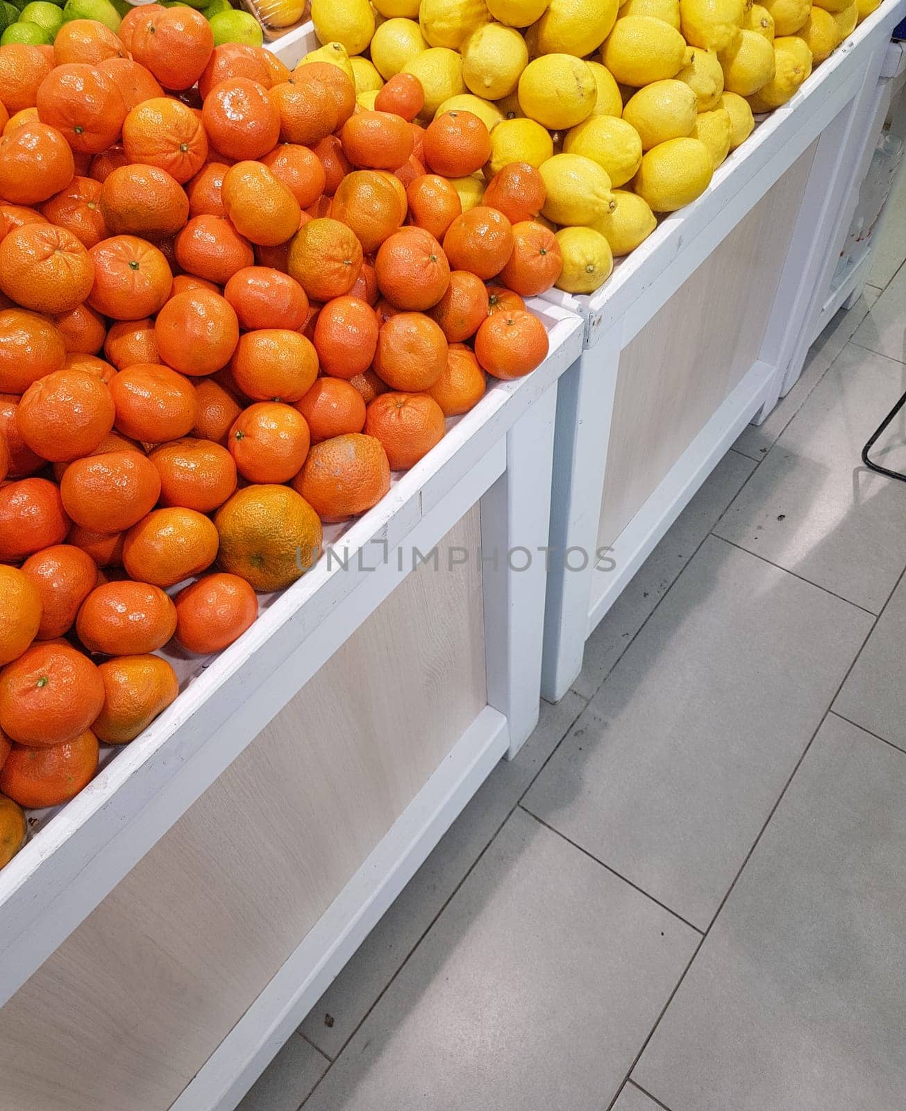 A counter with fresh tropical fruits, tangerines and lemons, close-up, vertical.