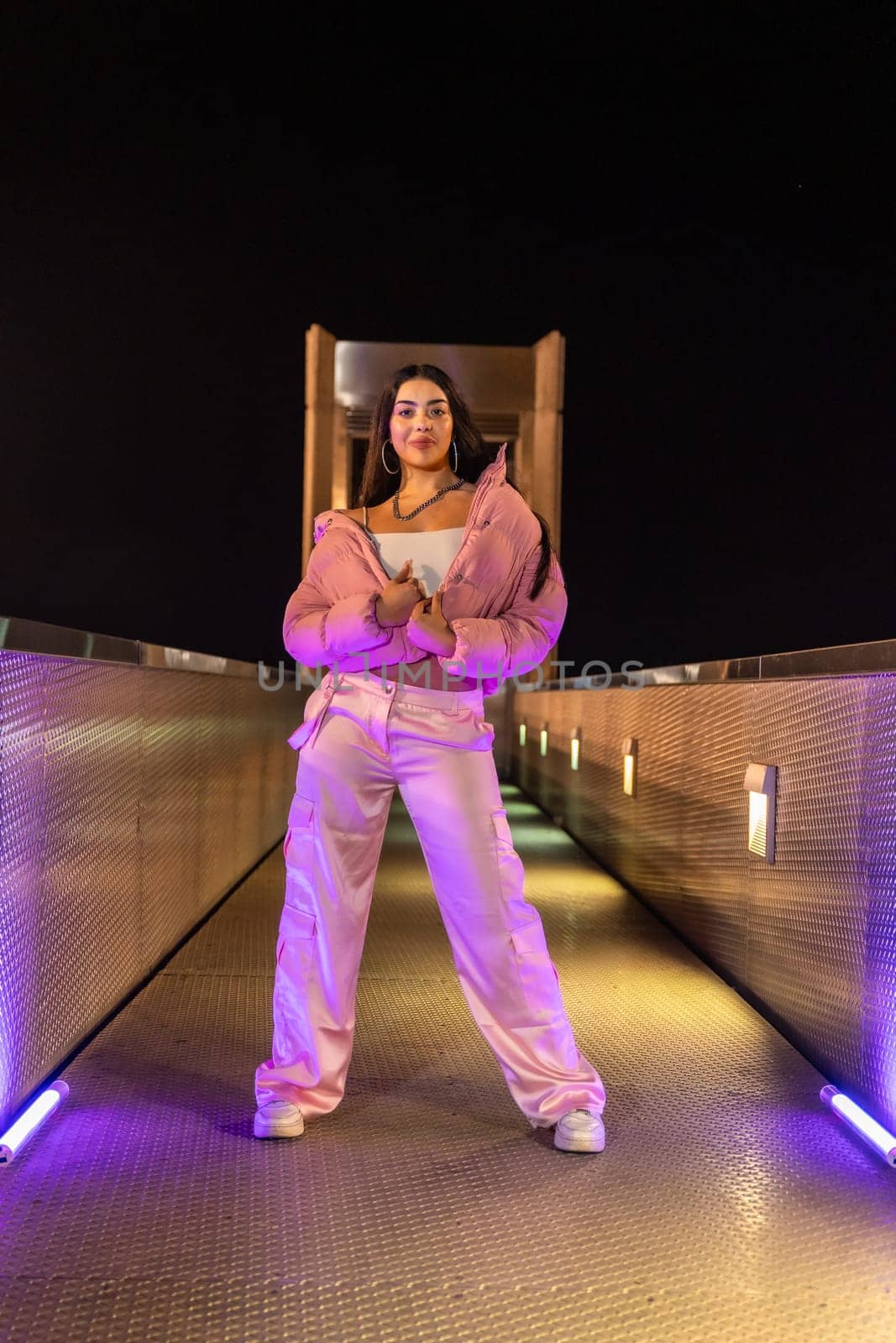 Urban teen with pink sportive clothes standing posing at night by Huizi