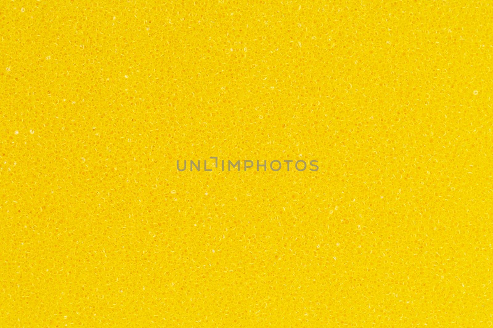 Bright yellow color foam sponge porous texture background. Extreme close-up view of detail abstract synthetic material. Horizontal composition
