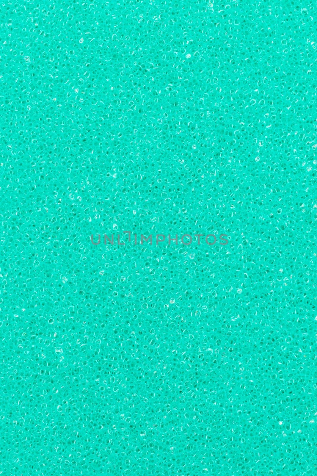 Turquoise color foam sponge porous abstract background. Extreme close-up view of detail synthetic textured material. Vertical composition for design, colored backdrop.