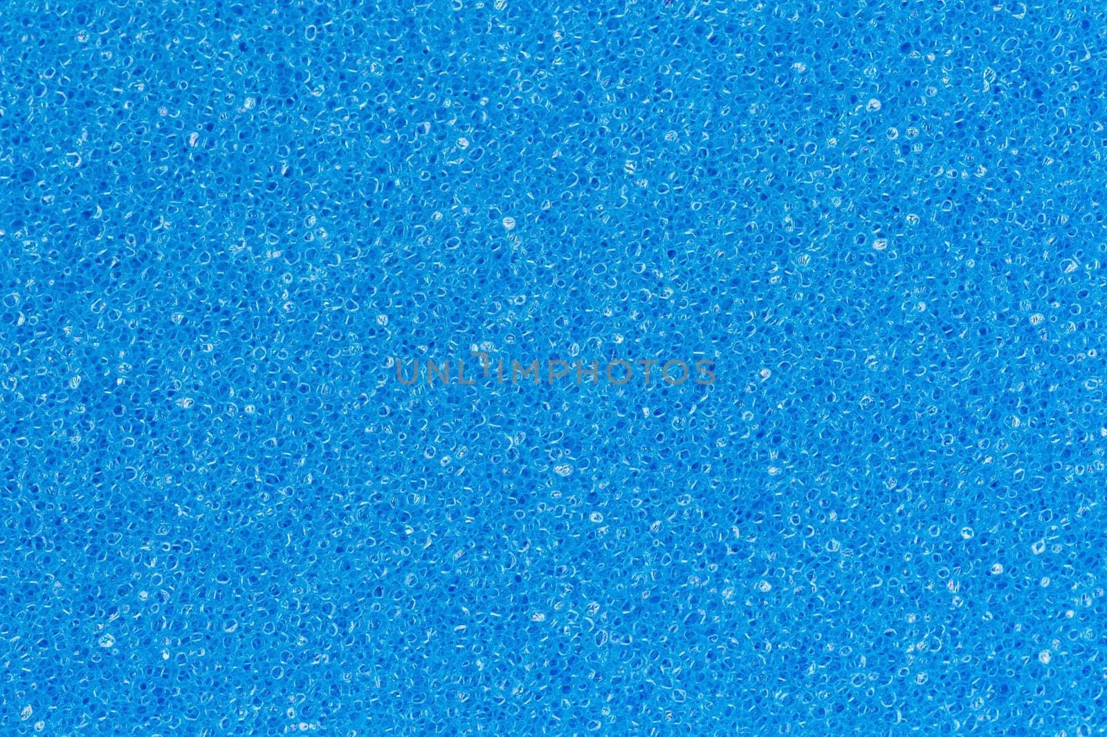 Foam sponge porous texture background deep sky blue color. Extreme close-up view of unique detail abstract synthetic material. Horizontal composition for design, colored decoration backdrop