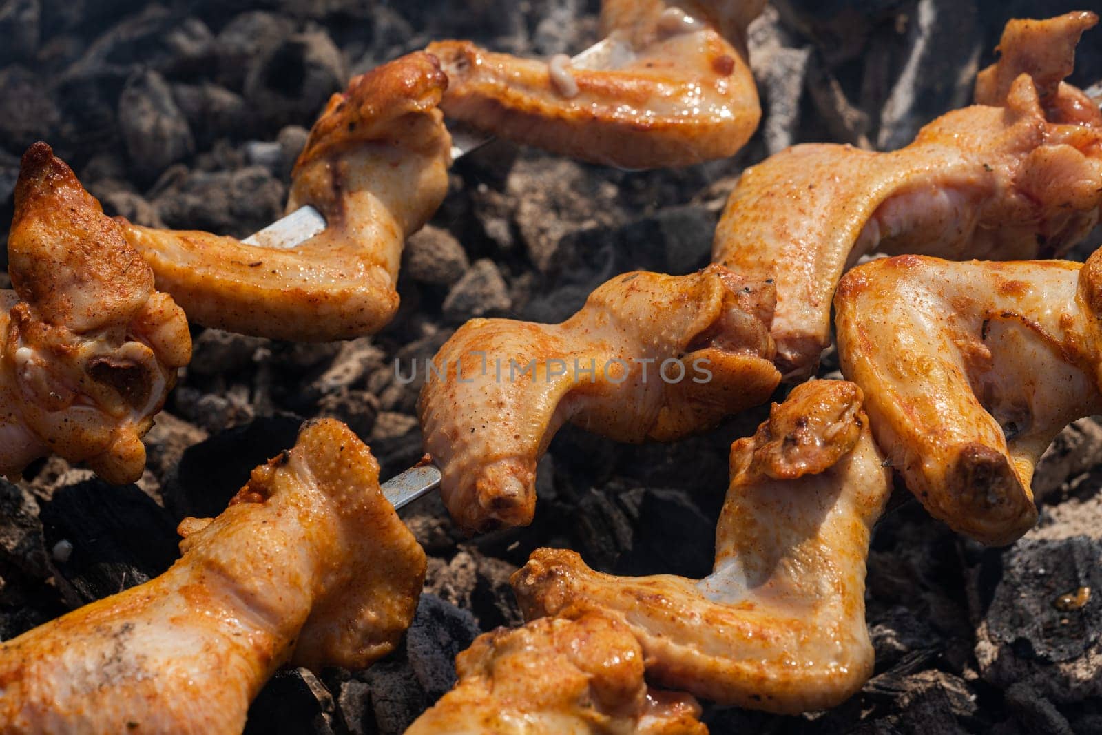 Juicy chicken barbecue on outdoors metal skewers on charcoal grill with fire smoke by Alexander-Piragis