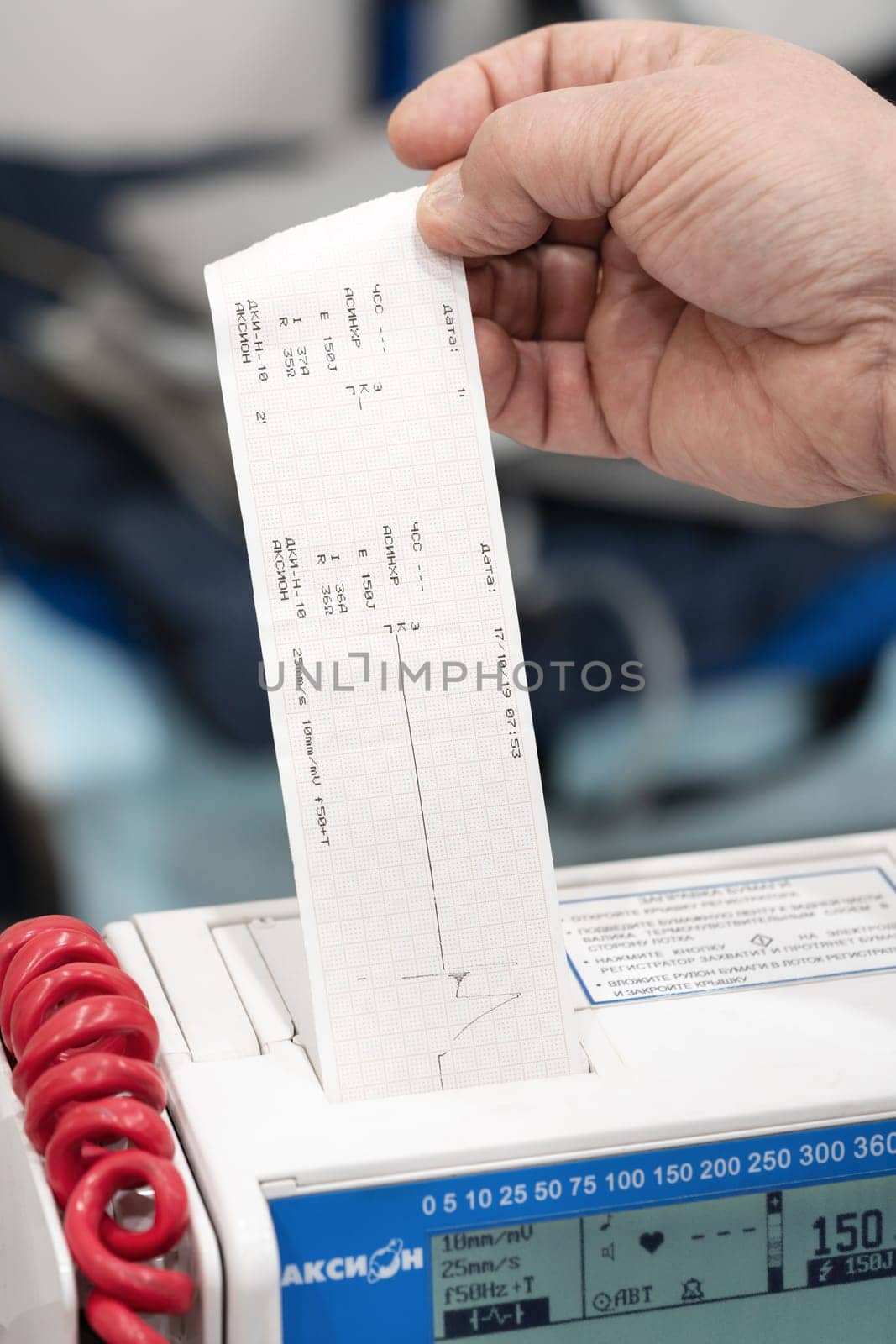 Doctor receives data from thermal printer at defibrillator monitor DKI-N-10 Axion for life-threatening cardiac dysrhythmias, non-perfusing ventricular tachycardia. Kamchatka, Russia - Oct 17, 2019
