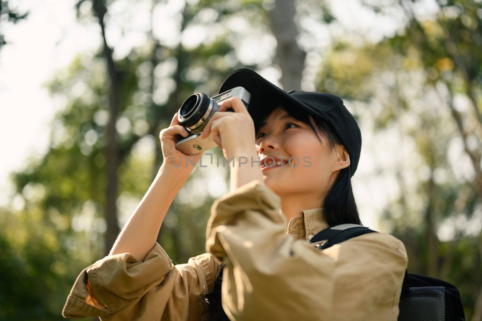 Smiling female tourist with a backpack taking pictures nature landscape with camera. Travel and active life concept.