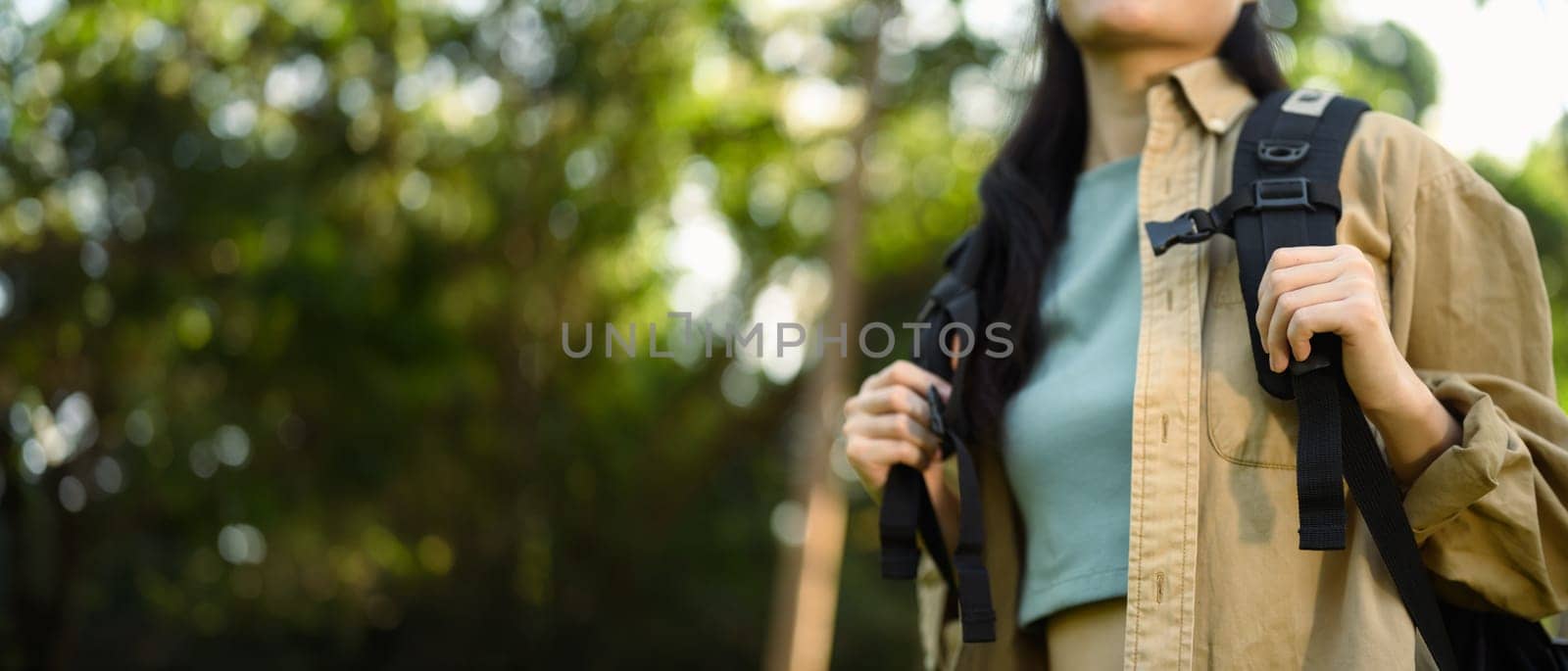 Cropped shot female tourist with backpack hiking at springtime. Travel and active life concept by prathanchorruangsak