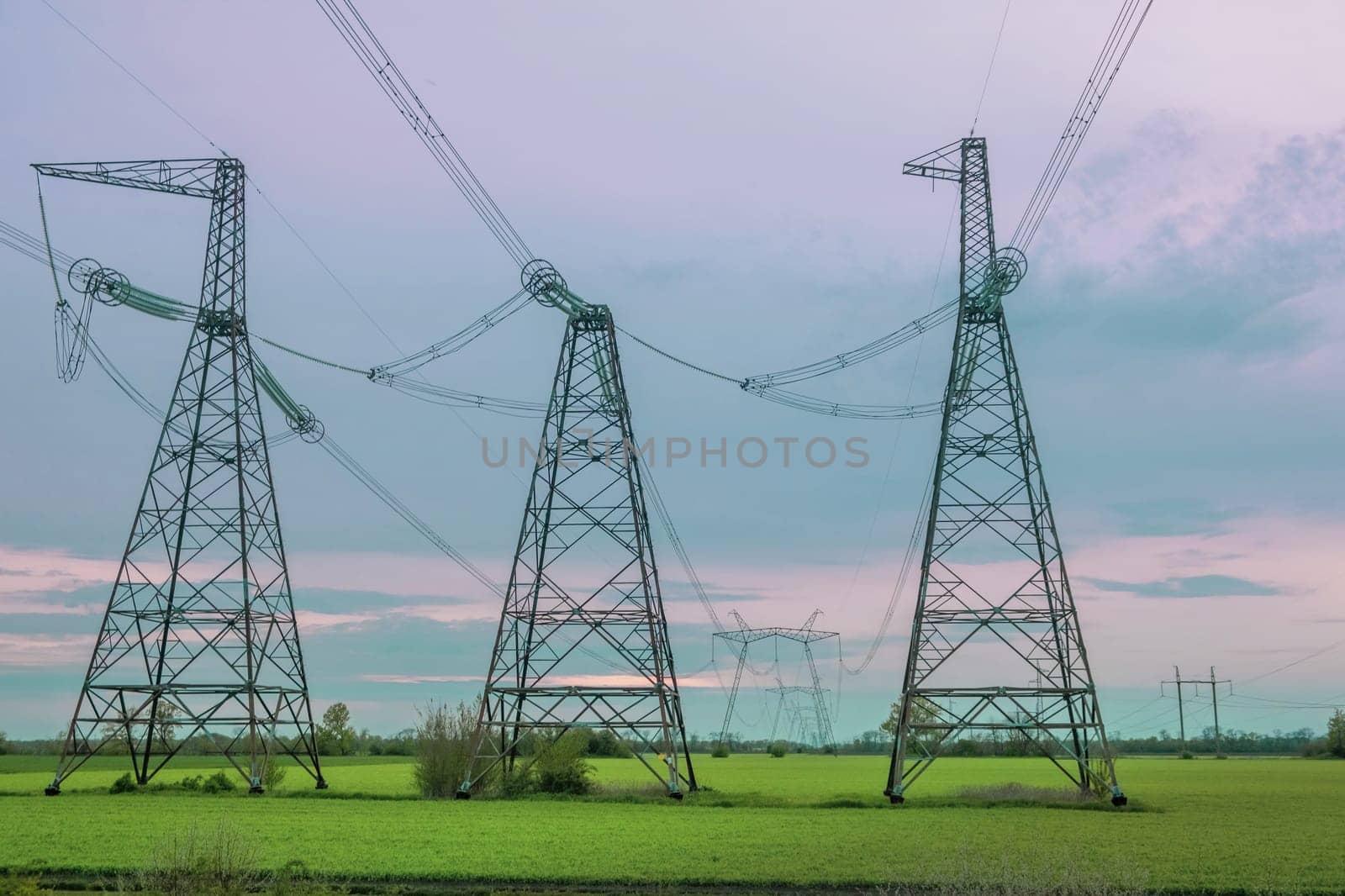 Group silhouette of transmission towers, power tower, electricity pylon, steel lattice tower at twilight. Texture high voltage pillar, overhead power line, industrial background. by igor010