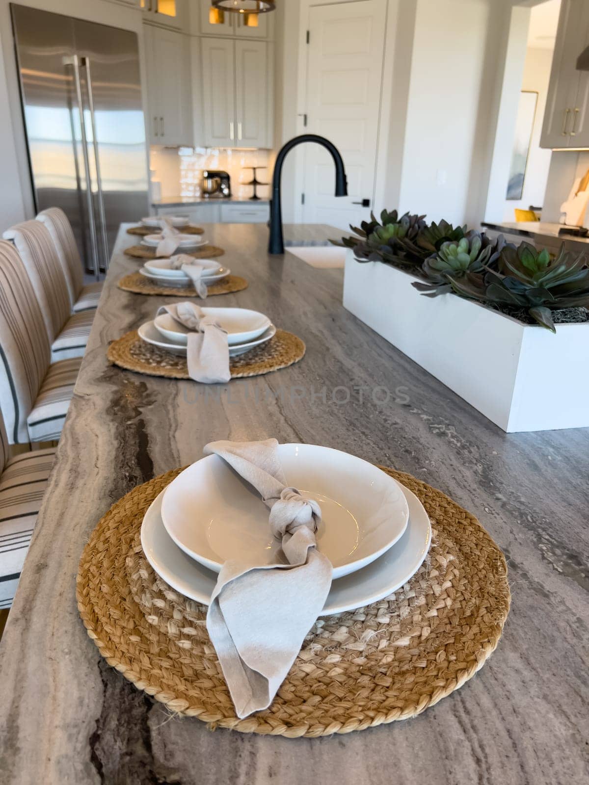 This inviting kitchen boasts a long dining table set for a family meal, with modern pendant lighting overhead and a sleek kitchen island that promises memorable gatherings and culinary adventures.