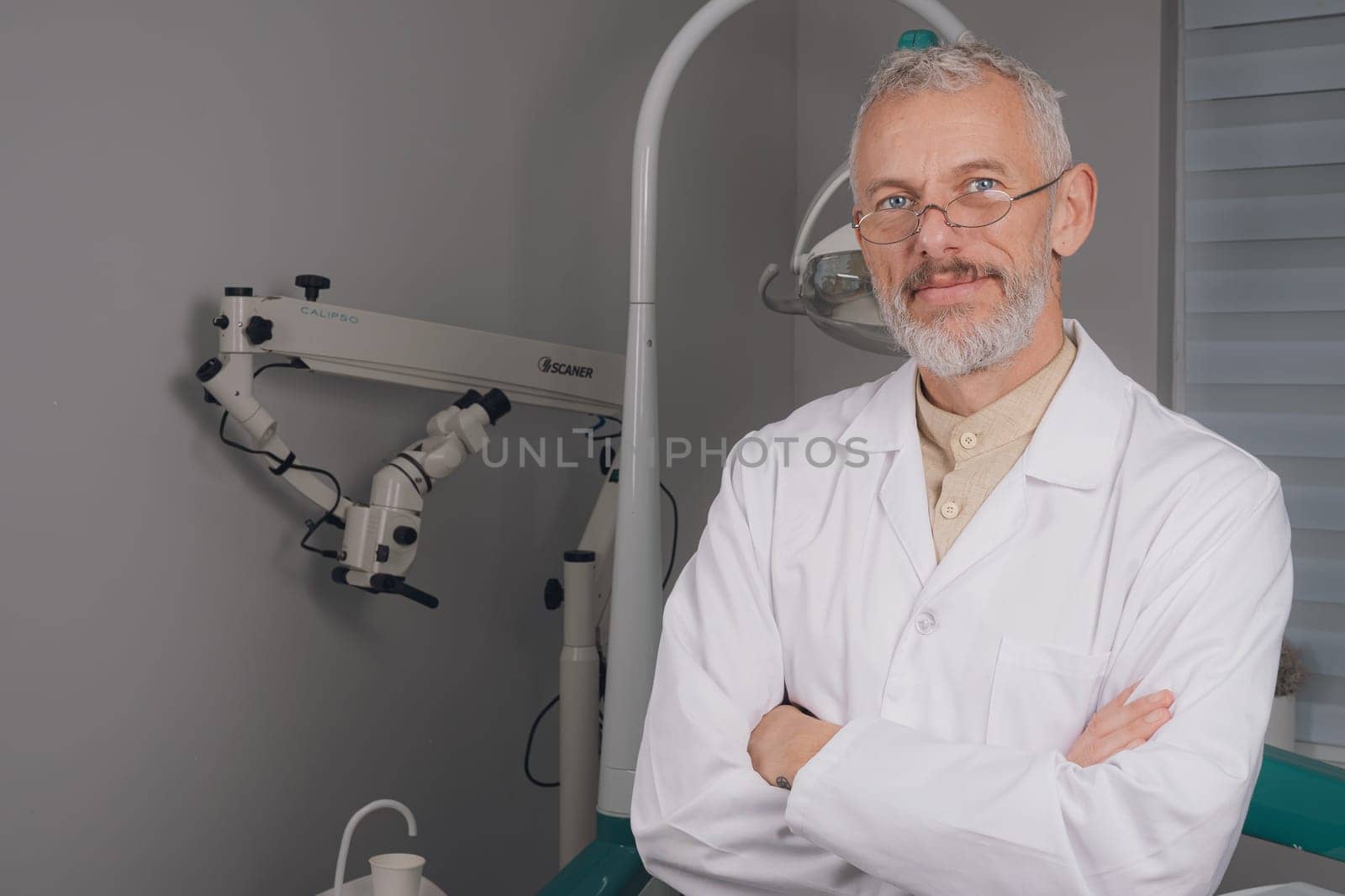 Portrait of attractive handsome dentist with haircut, white lab coat.