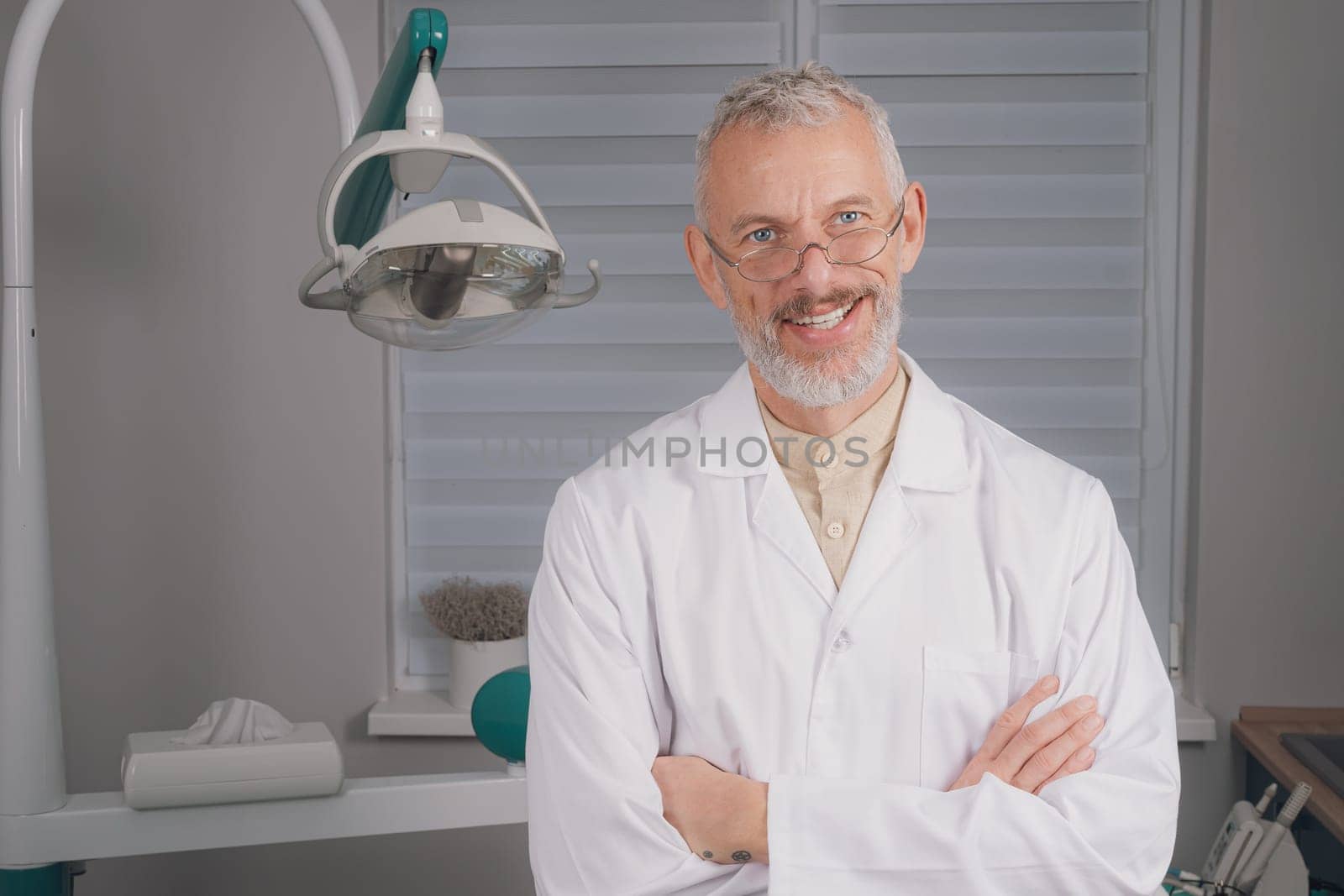 Male dental doctor wearing face sitting at his clinic. by Сookiestock