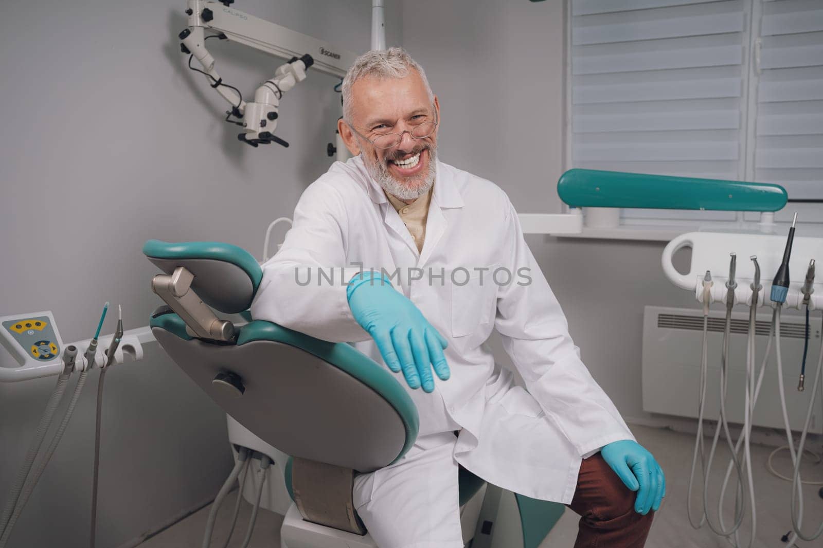 Male dental doctor wearing face sitting at his clinic. by Сookiestock