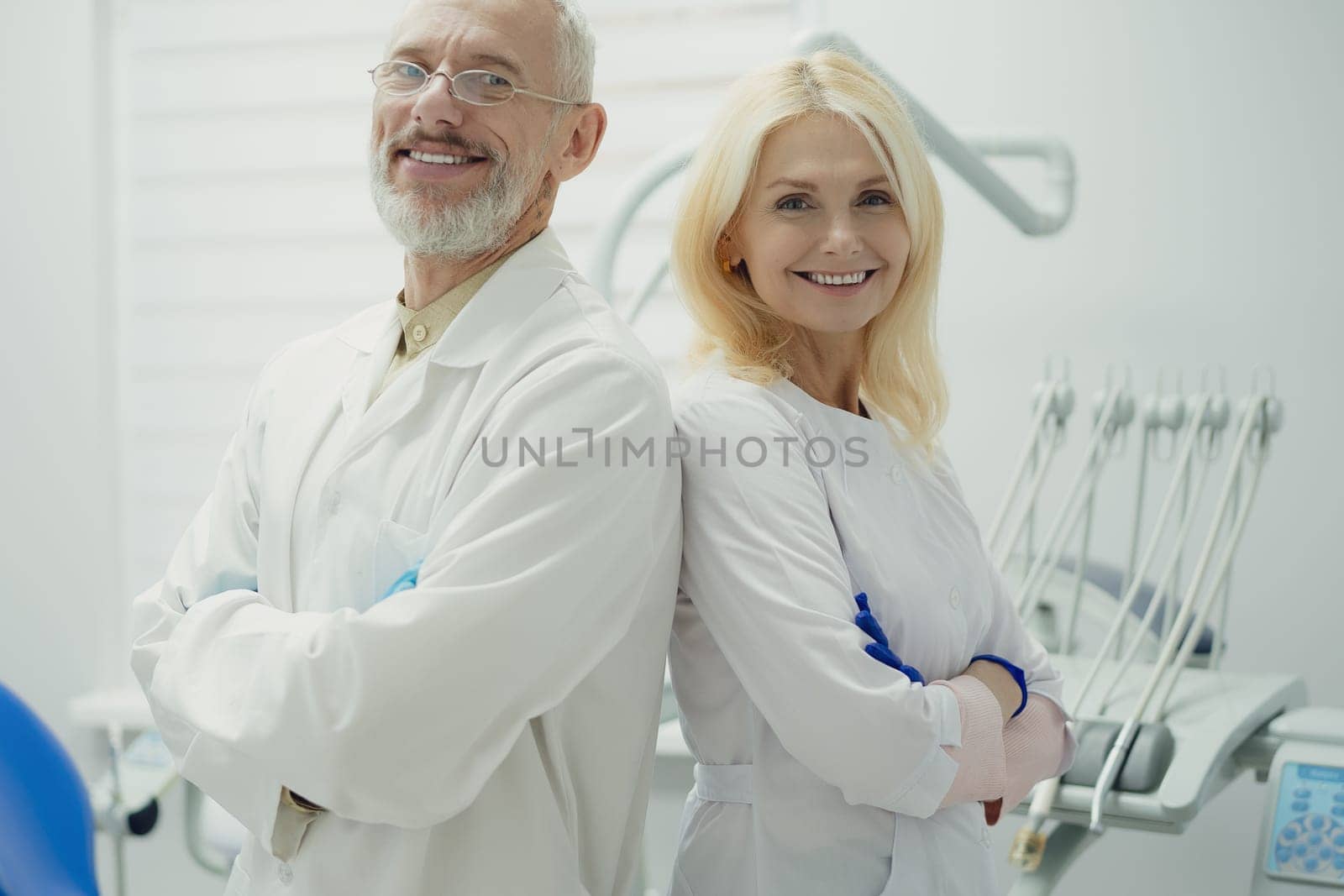 Male and female dental doctors wearing face sitting at his clinic. by Сookiestock