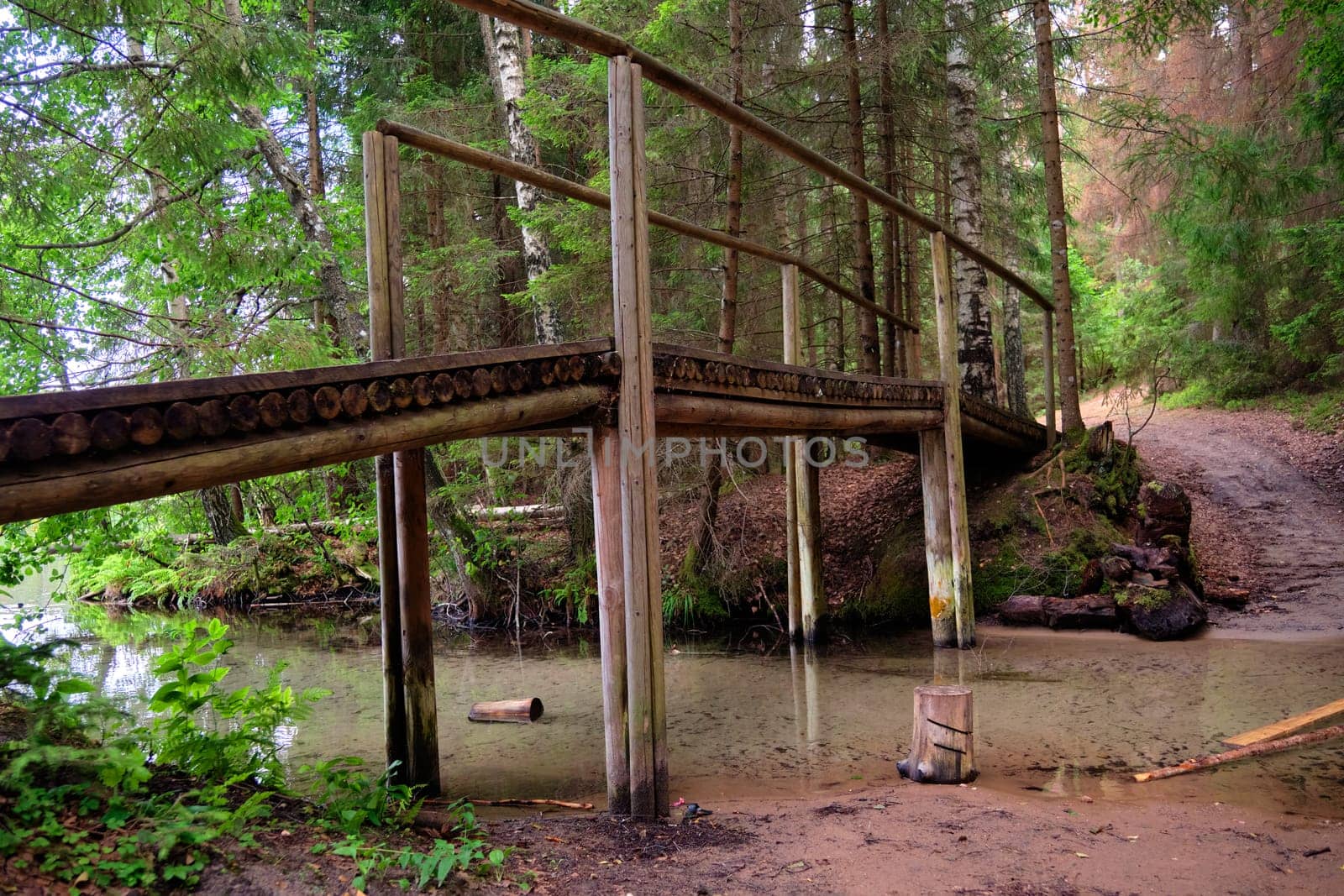 A wooden bridge in close-up over a stream in the forest, bottom view