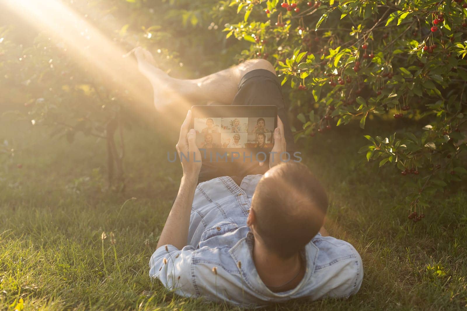 a man uses a tablet to chat in the garden.