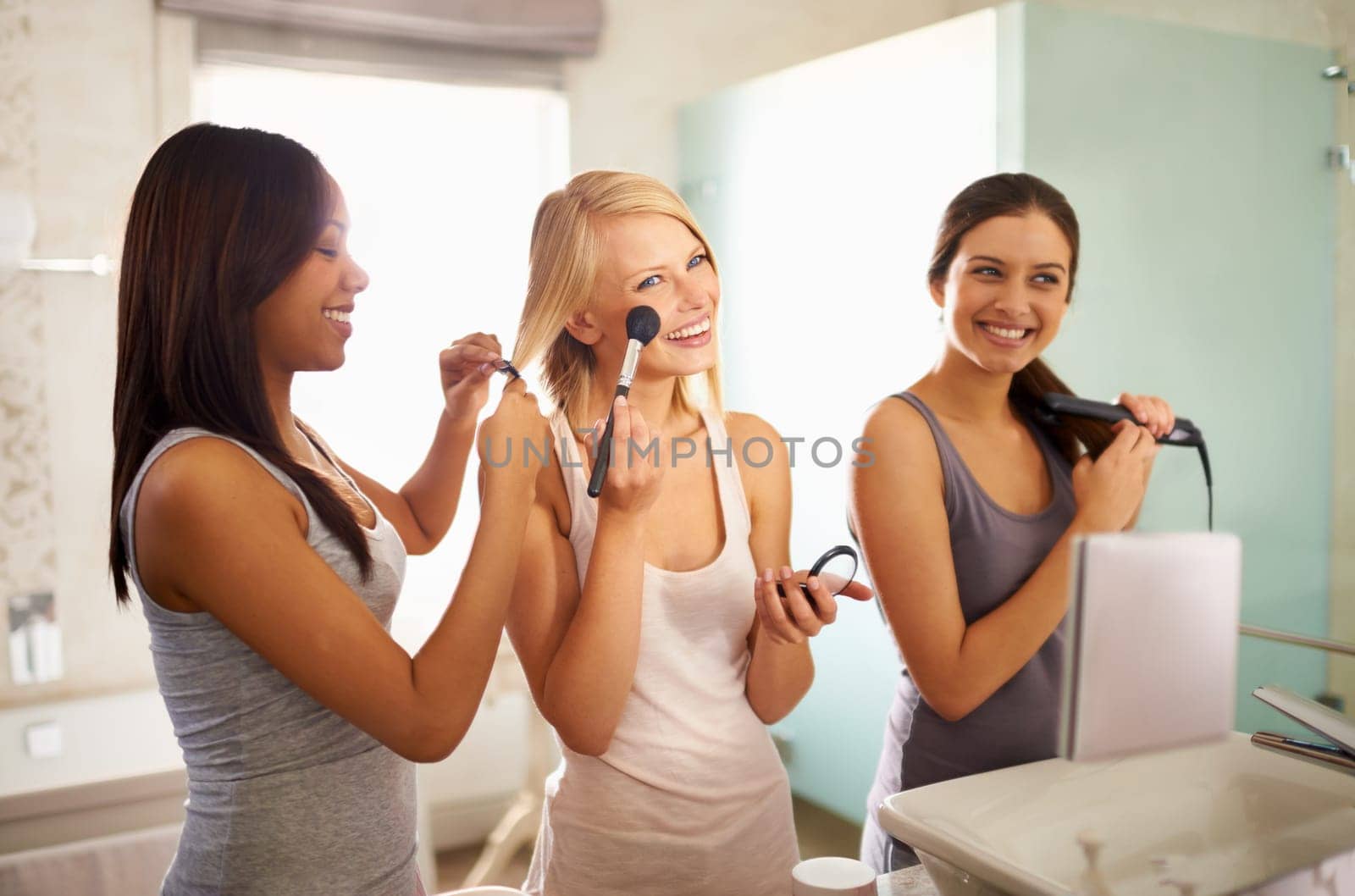 Mirror, friends and happy women in bathroom for makeup, skincare or beauty to prepare for party together at home. Group, cosmetics or smile of girls with reflection, hair straightener or laughing.