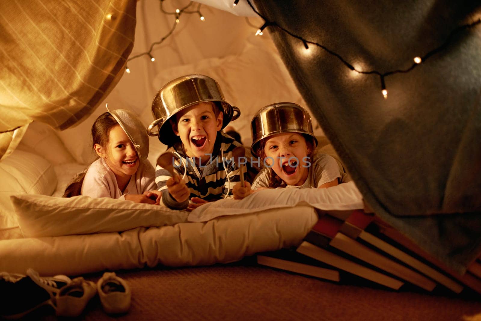 Tent, lights and portrait of children at night in bedroom for playing, fun and bonding at home. Friends, youth and happy kids with spoon, helmet pots and blanket fort for games, relax and childhood.