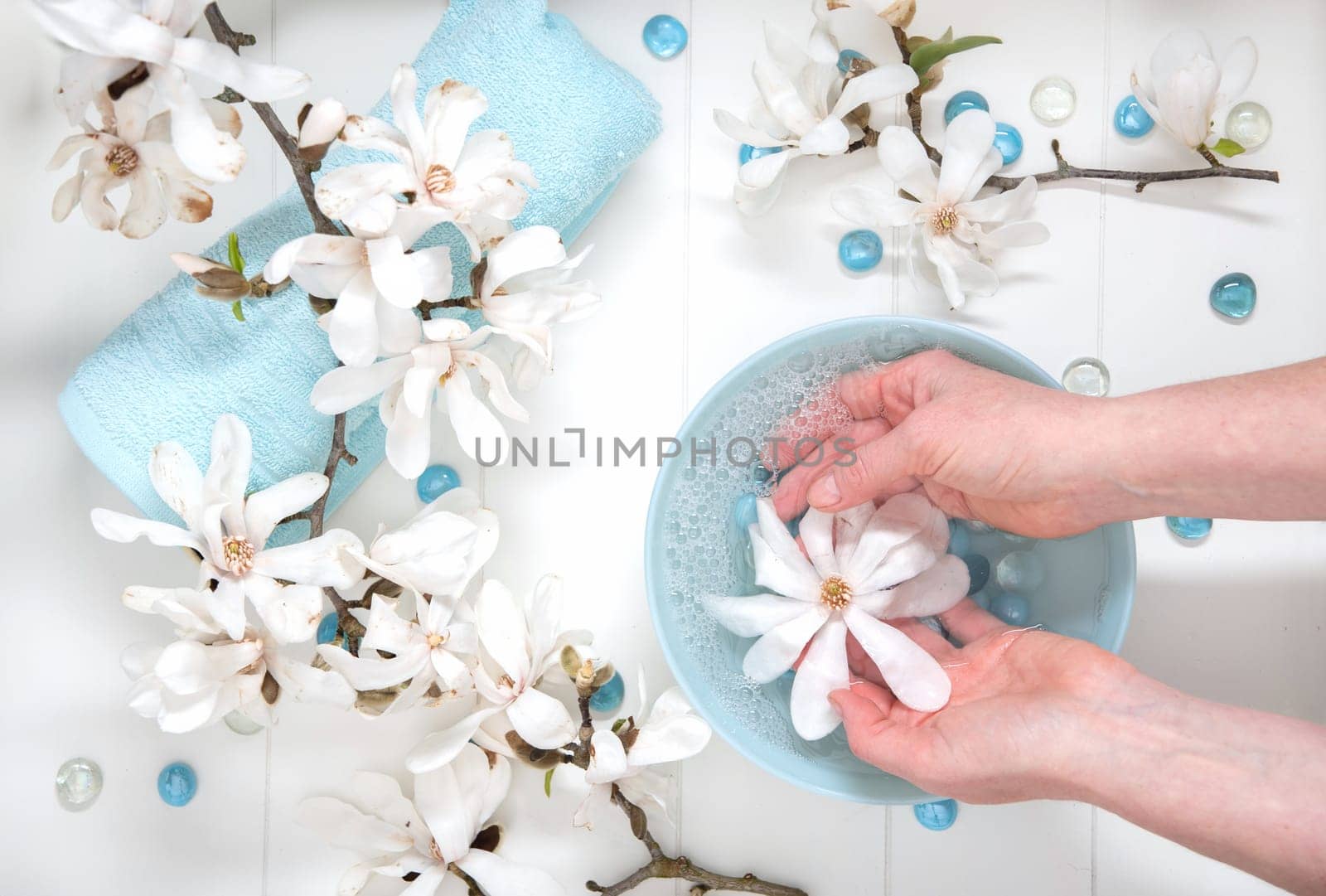 Hands of a young girl with natural manicure and a bowl of water with white magnolia flowers, spa treatments and massage, cosmetology personal care, High quality photo