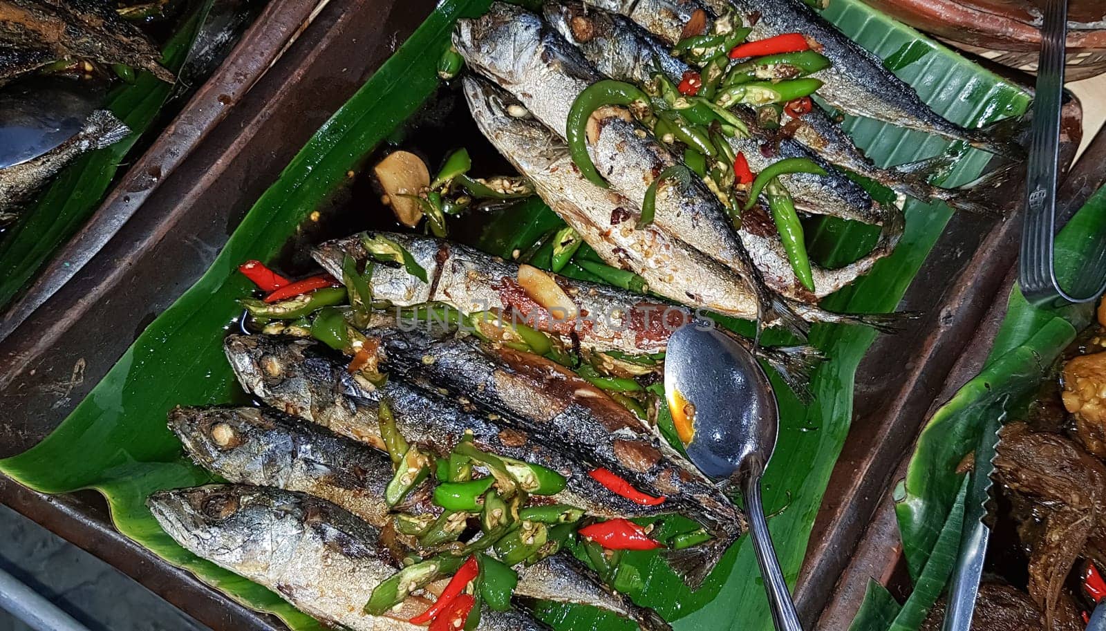 Seafood dish served on the table and plate from above with different kind of dish from fried fish barracuda, snapper, tuna jaws, and also mix of tropical vegetables and sambal or chili paste