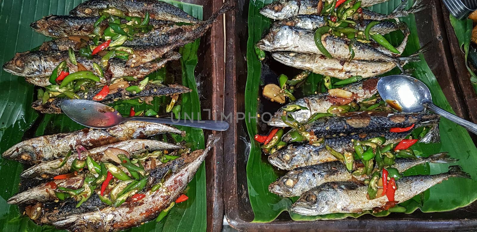Seafood dish served on the table and plate from above with different kind of dish from fried fish barracuda, snapper, tuna jaws, and also mix of tropical vegetables and sambal or chili paste