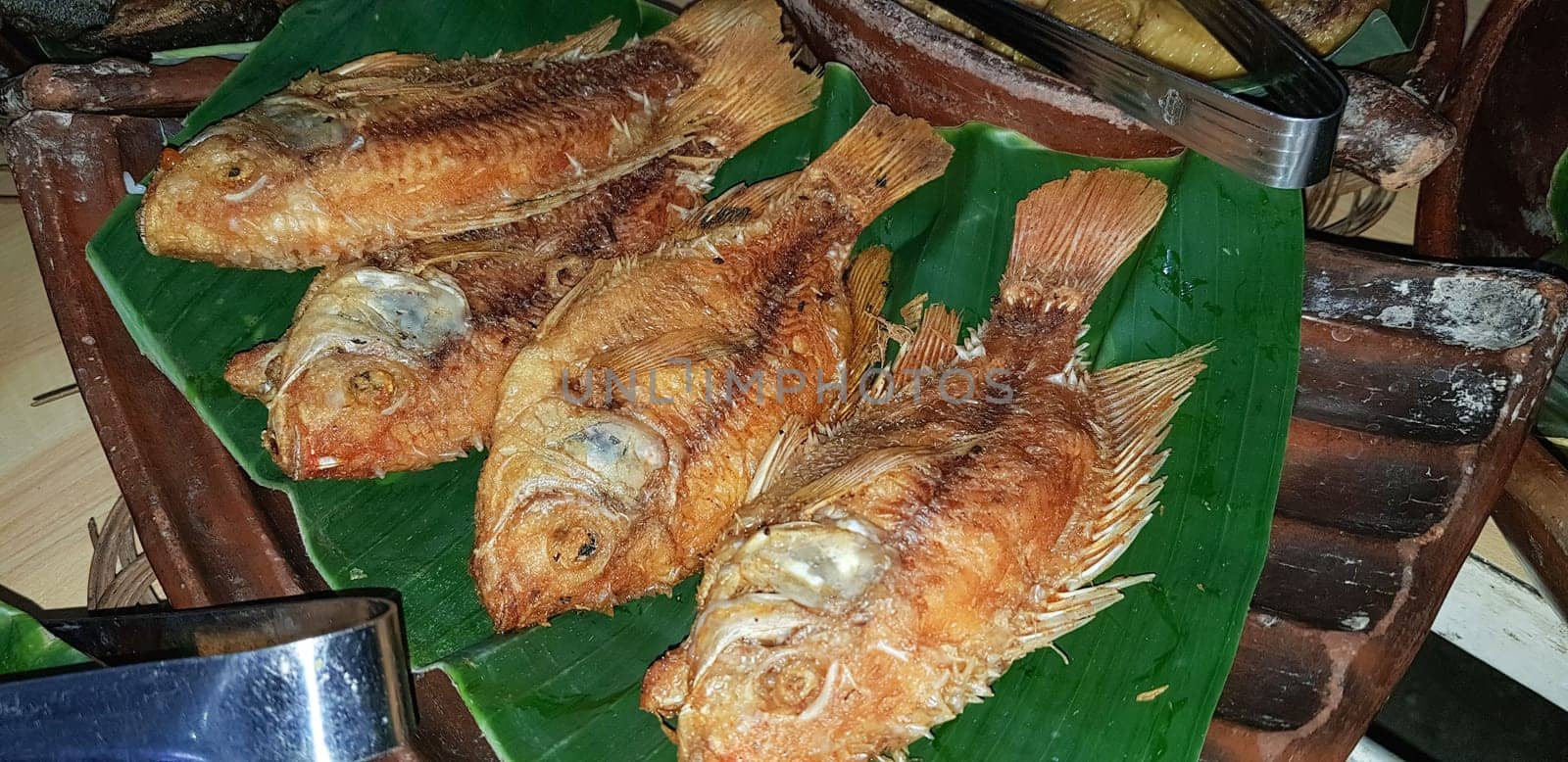 Seafood dish served on the table and plate from above with different kind of dish from fried fish barracuda, snapper, tuna jaws, and also mix of tropical vegetables and sambal or chili paste