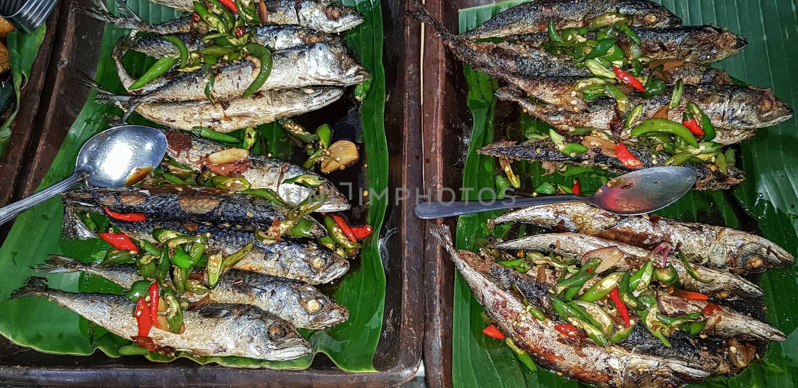 Seafood dish served on the table and plate from above with different kind of dish from fried fish barracuda, snapper, tuna jaws, and also mix of tropical vegetables and sambal or chili paste