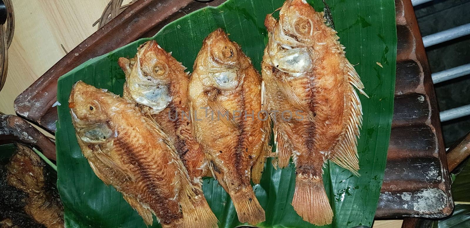 Seafood dish served on the table and plate from above with different kind of dish from fried fish barracuda, snapper, tuna jaws, and also mix of tropical vegetables and sambal or chili paste