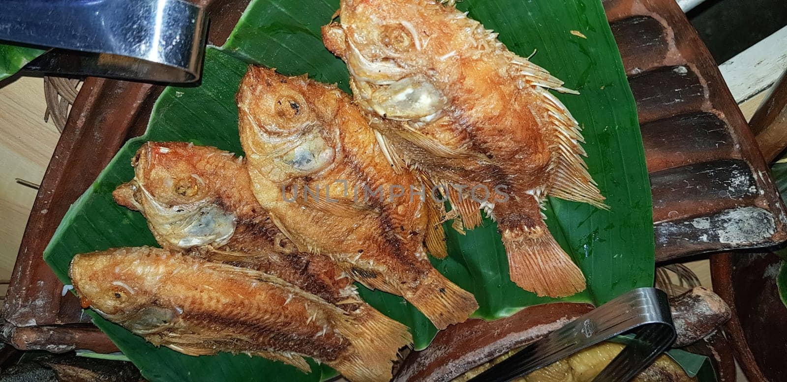Seafood dish served on the table and plate from above with different kind of dish from fried fish barracuda, snapper, tuna jaws, and also mix of tropical vegetables and sambal or chili paste
