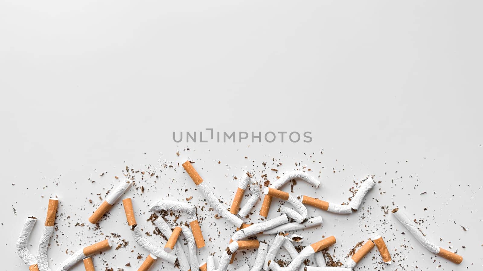 Discarded crushed broken cigarettes and scattered tobacco on white background, representing cessation and the end of smoking with copy space. No tobacco day. High quality photo