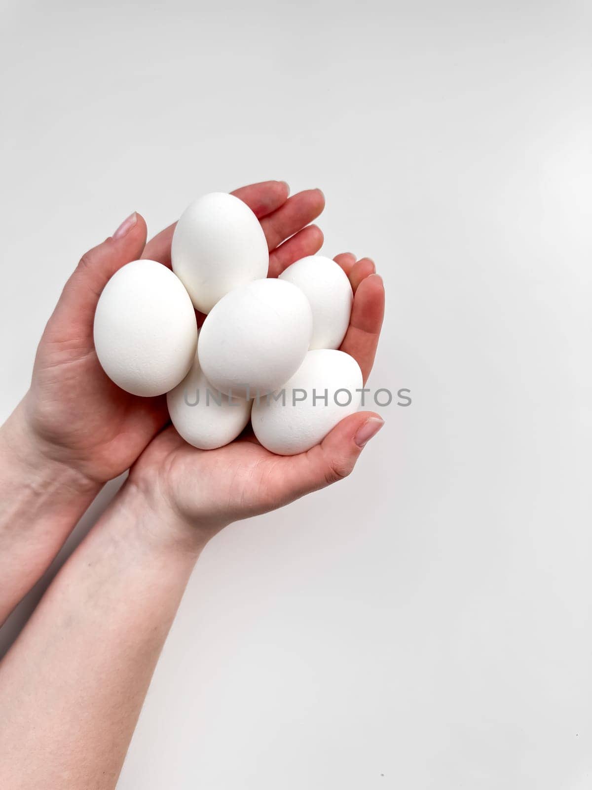 Hands cradling a cluster of white eggs against pale background, a symbol of care, nourishment, and new beginnings with ample copy space. For culinary websites, recipe blogs, and nutritional guides. by Lunnica