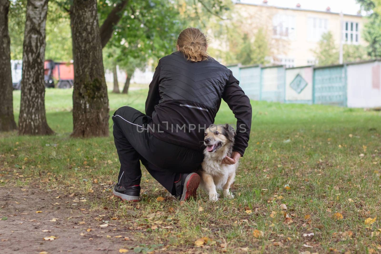 Man and dog walking in autumn park close up